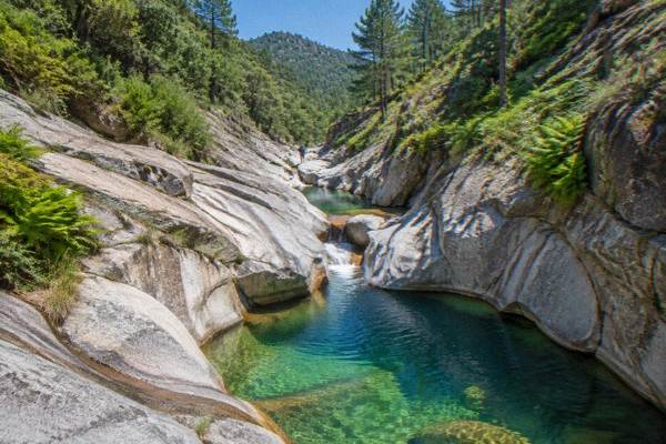 Canyoner abseiling down a smooth granite chute into a green pool