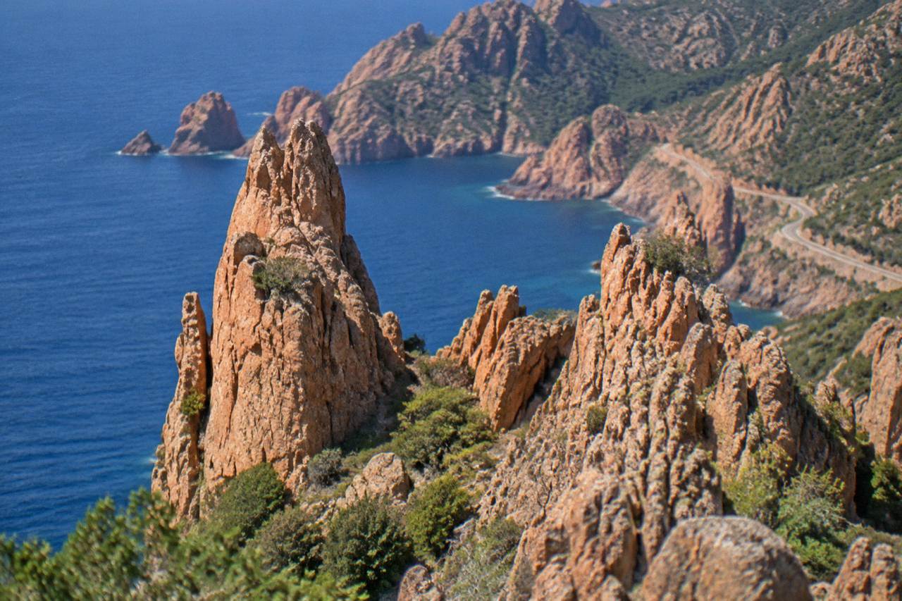 Red granite rock formations of the Calanques de Piana rising above the sea on the west coast of Corsica
