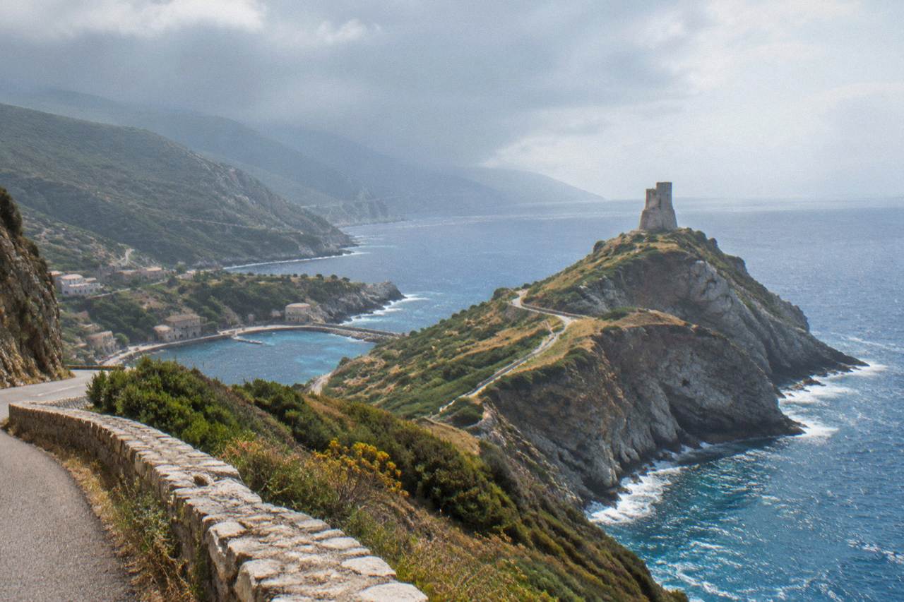 Rain clouds passing over the Corsican coastline with dark cliffs and a rough sea