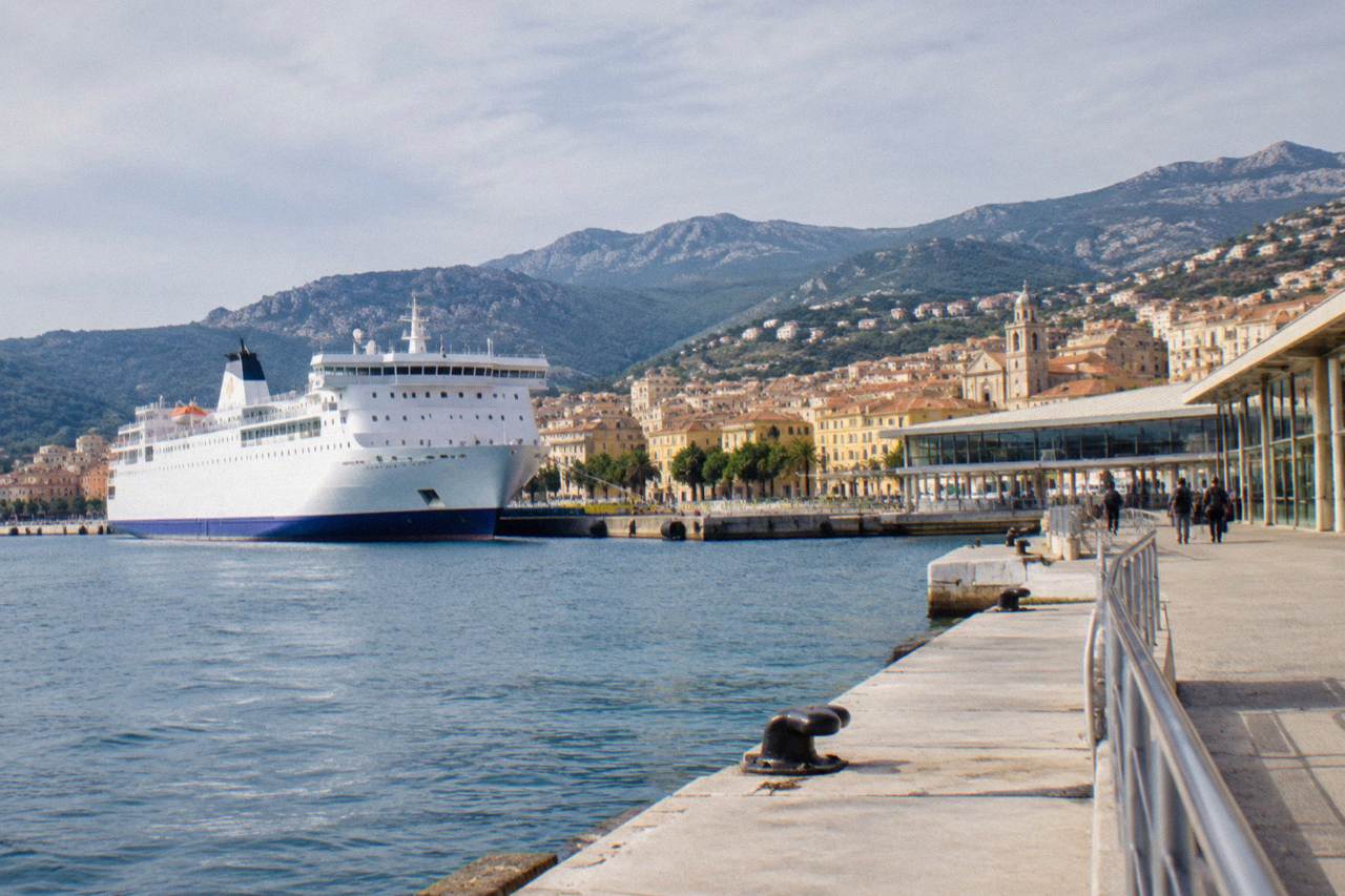 A ferry sailing into a Corsican harbour with mountains rising behind the town