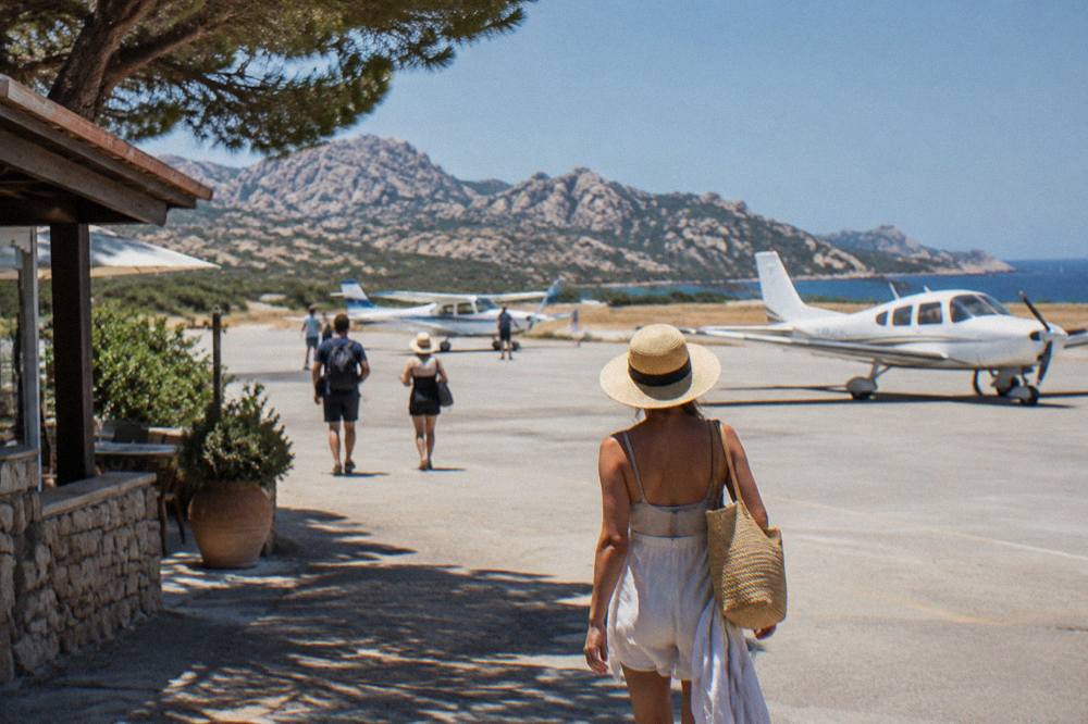 A small airport apron beside the Corsican coastline with light aircraft parked in summer light