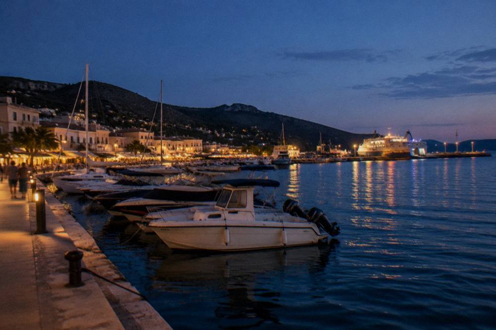 A Corsican harbour town at dusk with boats moored along the quay below hills