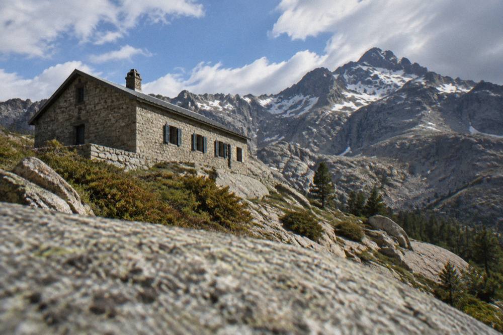 A stone refuge building on a granite slope high in the Corsican mountains