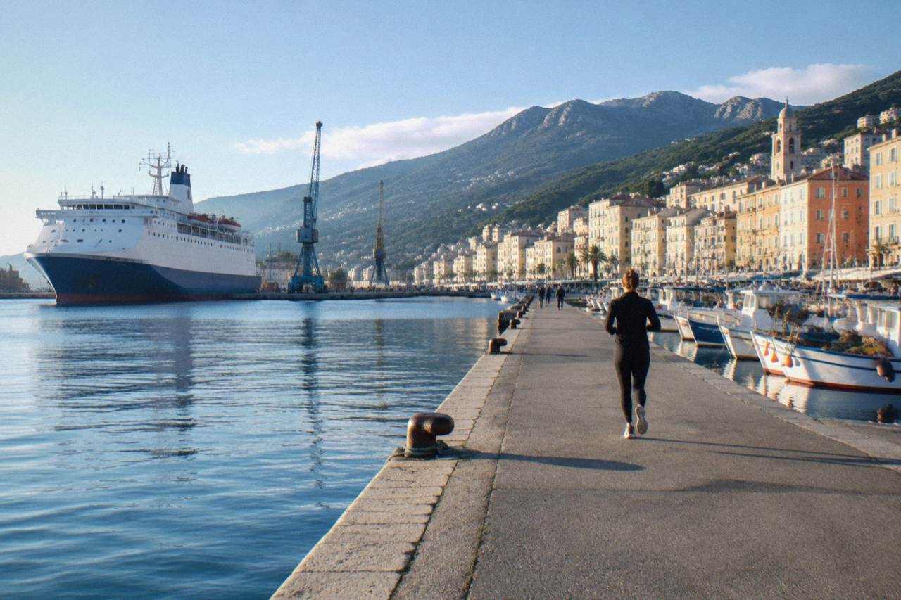 Fishing boats moored in the old port of Bastia with pastel buildings on the quay