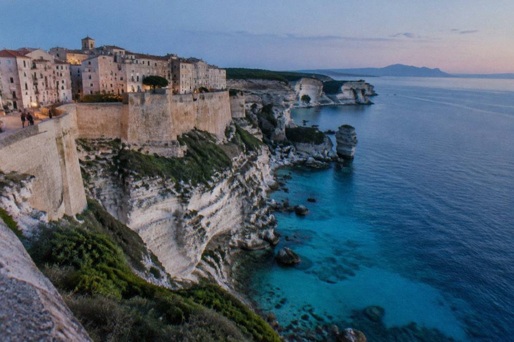 White cliffs and turquoise water along the coastline south of Bonifacio with Sardinia on the horizon