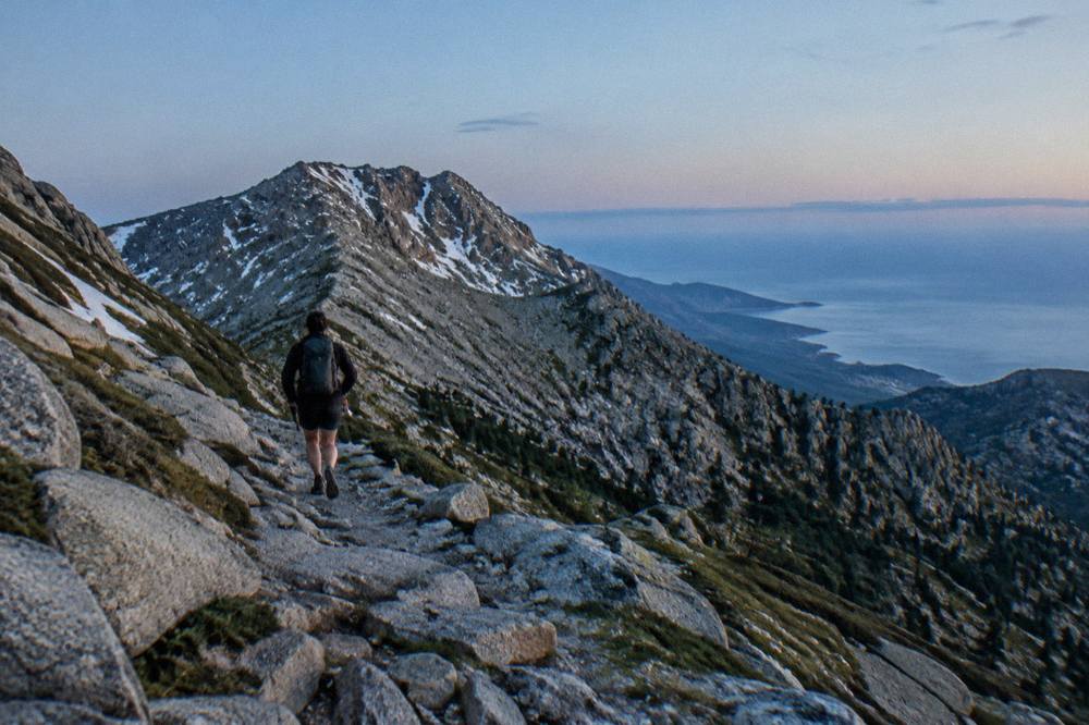 Hikers on a rocky ridge path with the Mediterranean sea in the distance