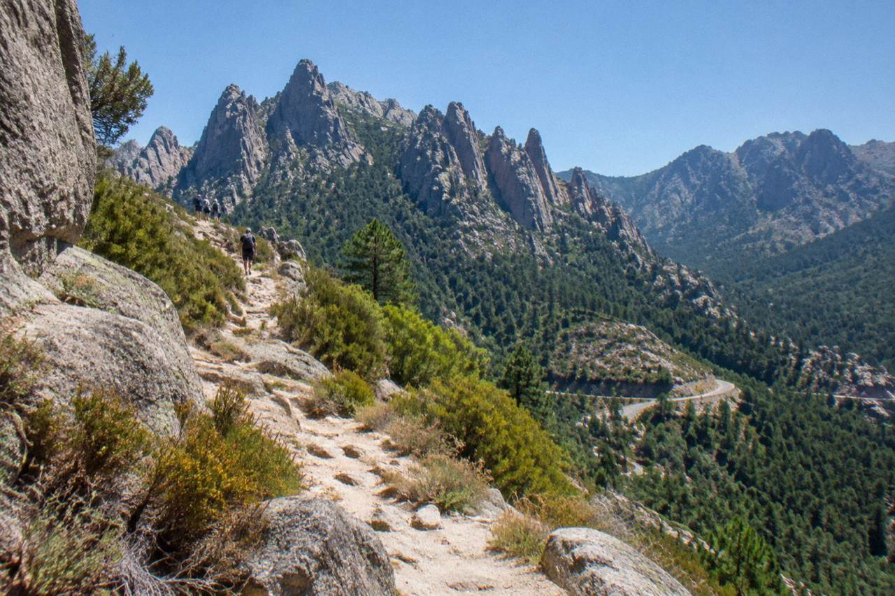 A rocky mountain ridge path in Corsica with granite peaks under a clear sky