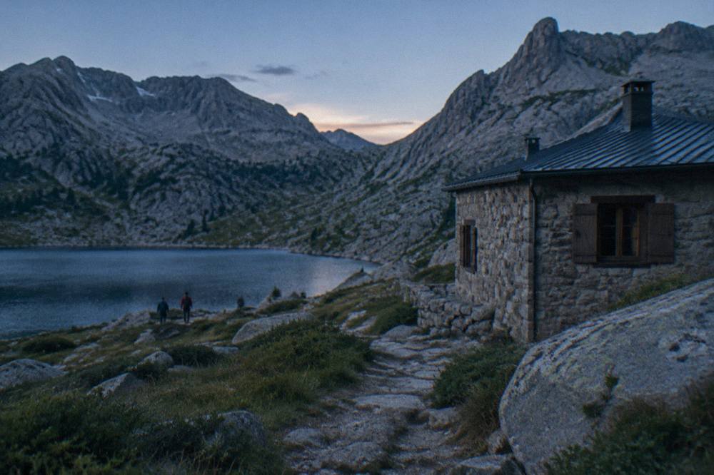 A mountain refuge building beside a stony path among Corsican granite slopes