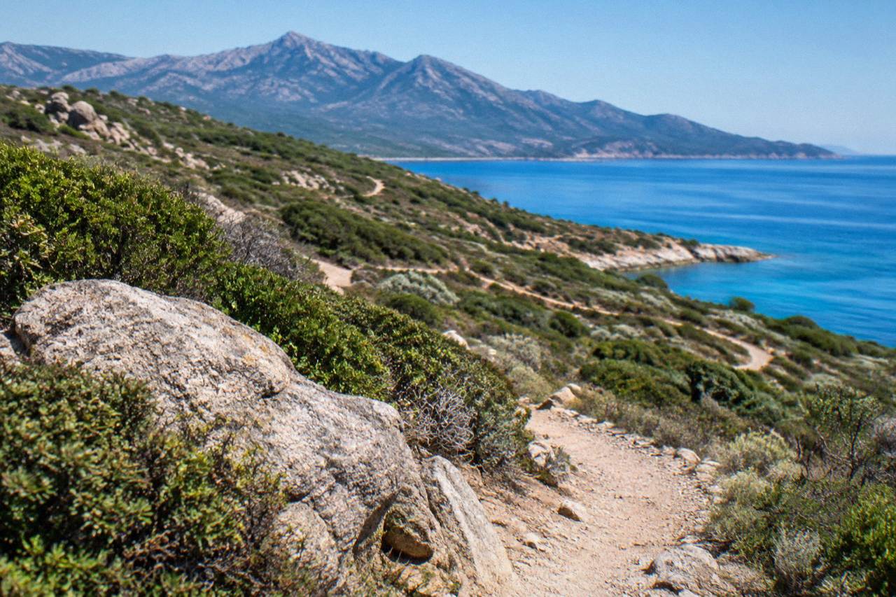 Corsican mountains rising above the Mediterranean coastline with a calm sea below