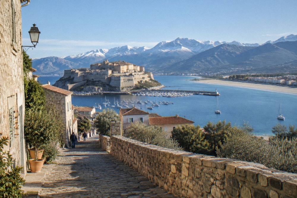 A stone village street with mountains in the background in southern Corsica