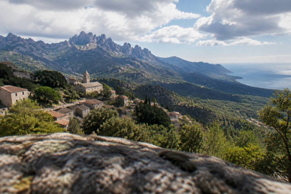 A wide view of forested mountains rolling toward the southern Corsican coast
