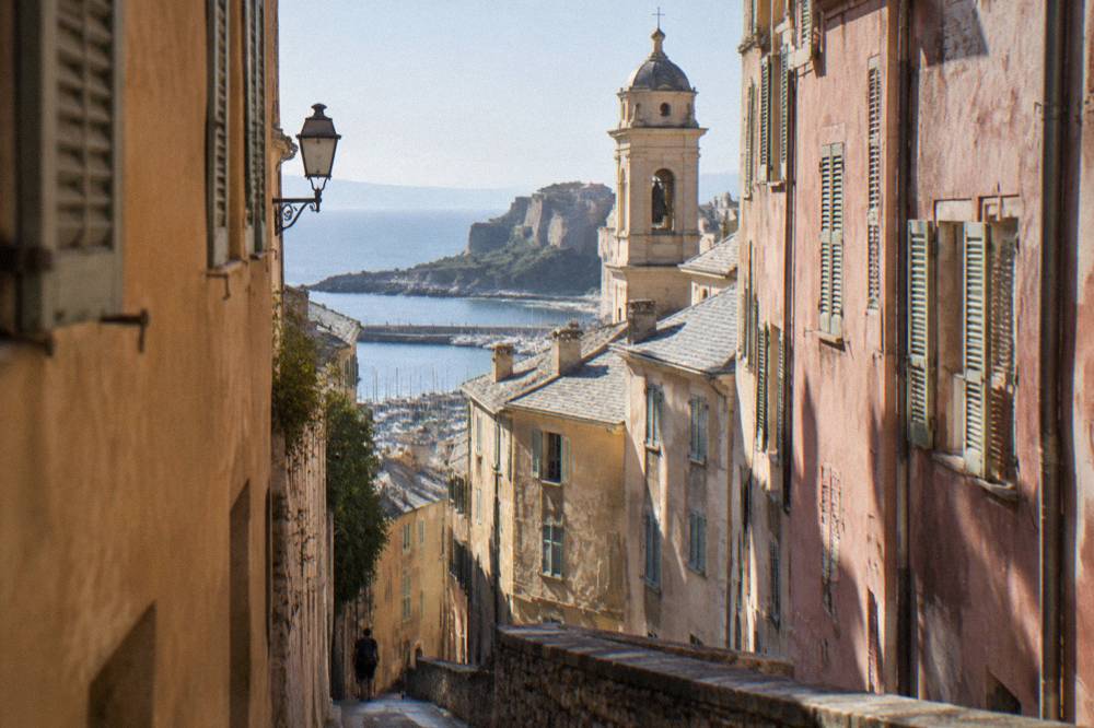 A narrow street in the old quarter of Bastia with tall shuttered buildings and a church tower