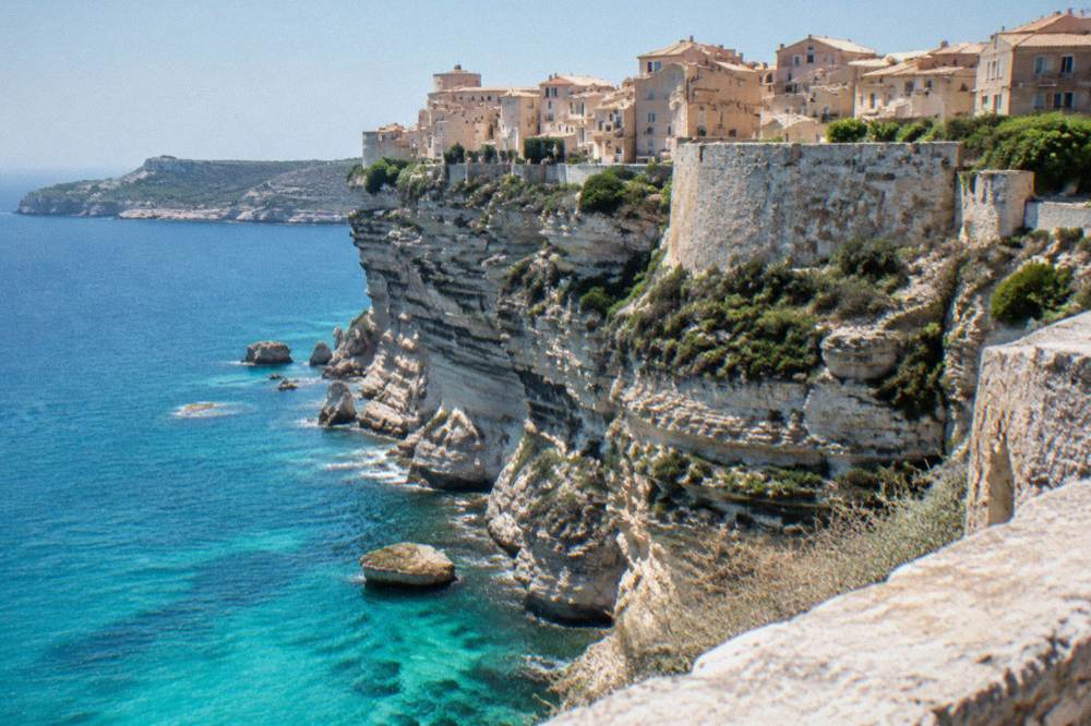 Walled town on white cliffs above a turquoise strait