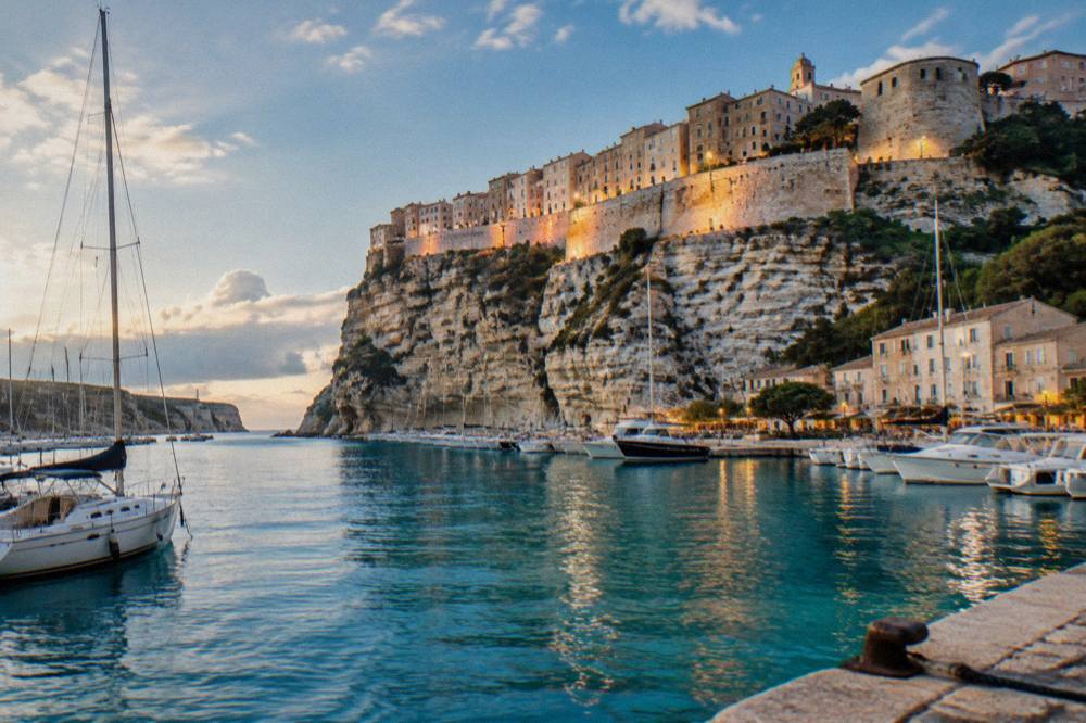 Boats moored in Bonifacio marina in the evening with the illuminated old town above