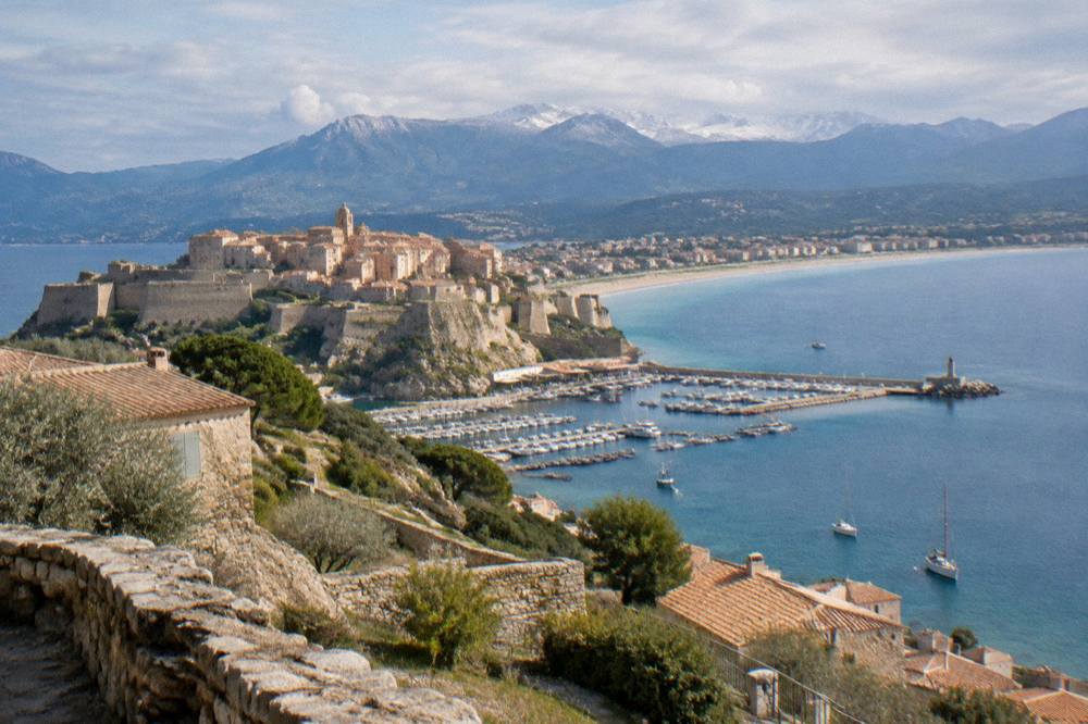 A stone hilltop village with terraced slopes and sea haze in the distance