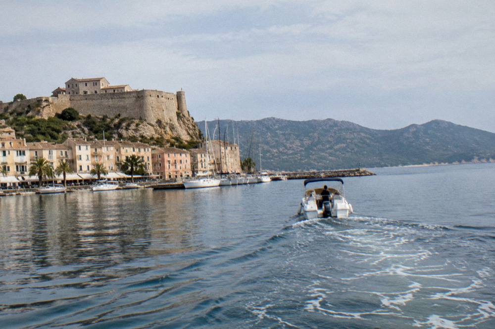 A boat leaving Saint-Florent harbour toward the Agriates coastline in Corsica