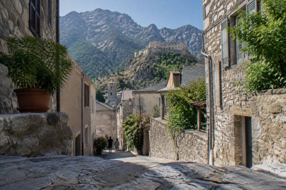 Narrow stone streets and old houses in the centre of Corte with mountains behind
