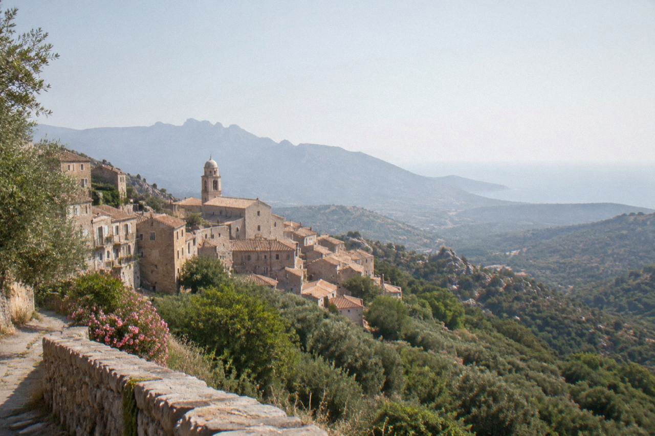 Stone houses of a hill town above the green hills of southern Corsica