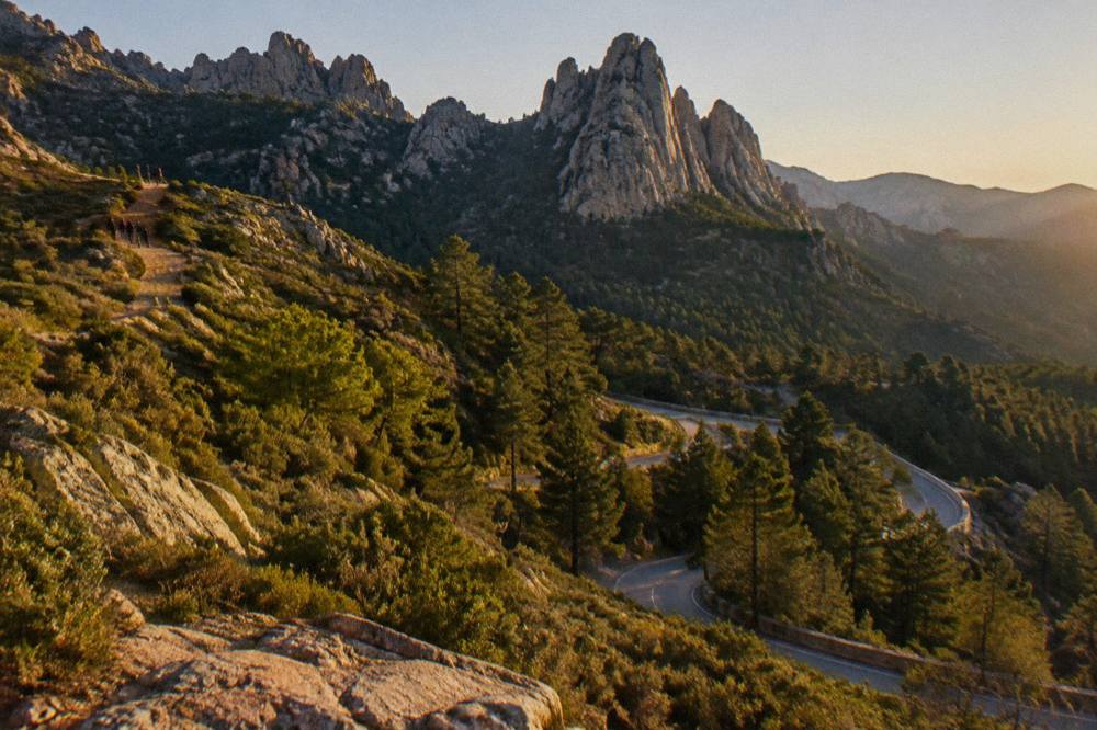 Jagged granite needles above dark pine forest under a clear sky