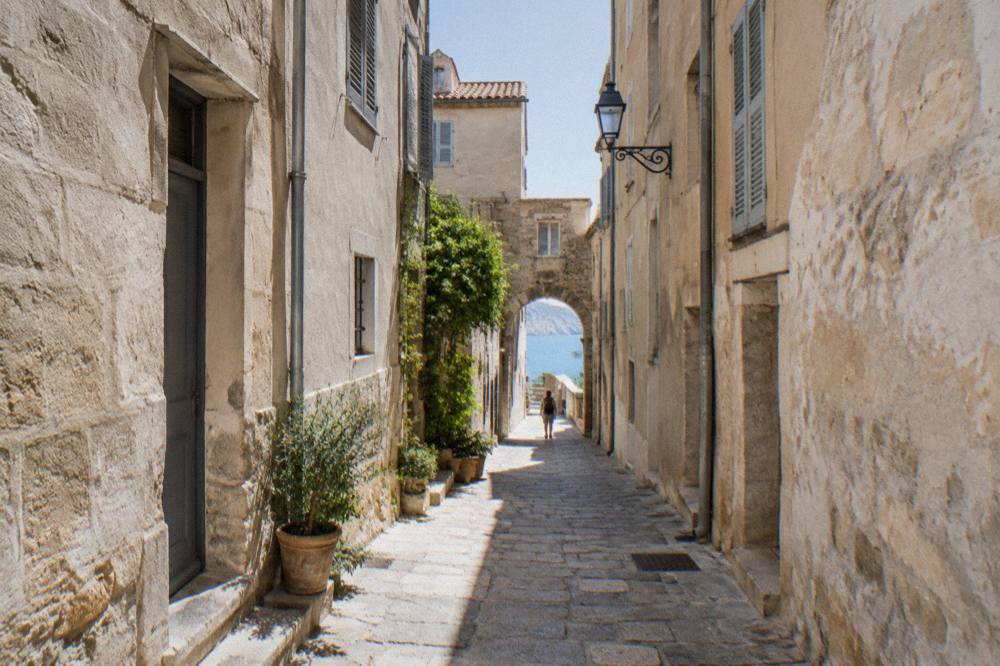 Tall pale houses and ramparts at the edge of undercut white limestone cliffs above bright turquoise sea