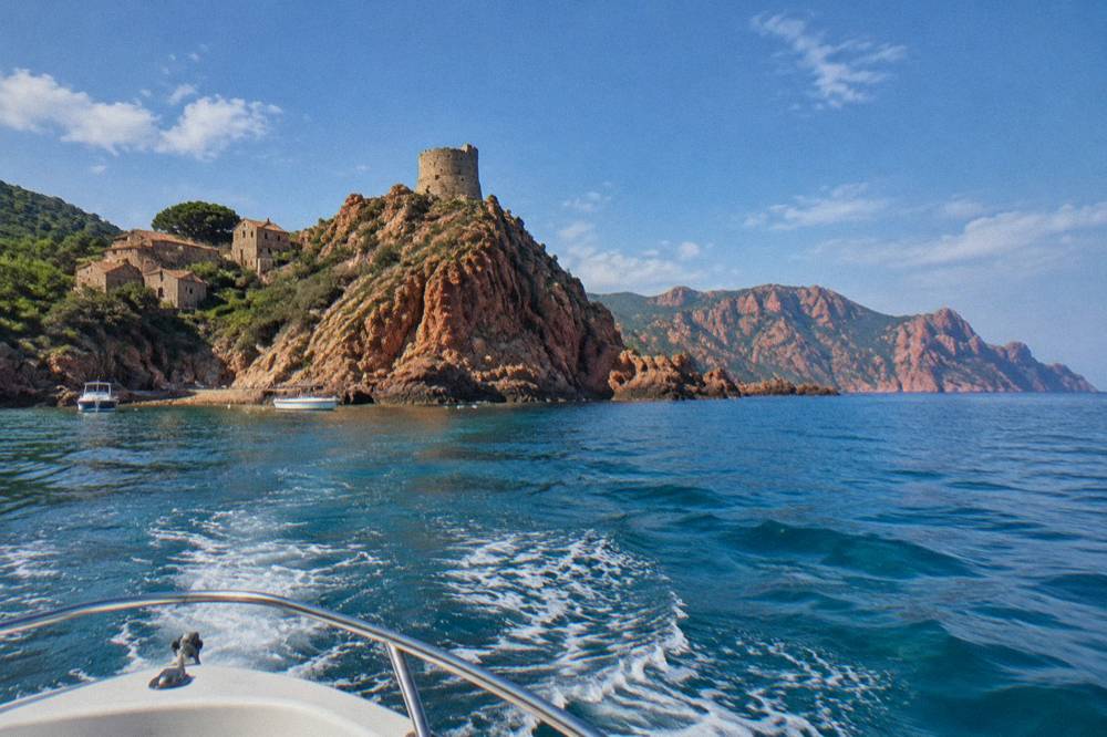 Boat heading out from a Corsican harbour toward red rock cliffs on the horizon