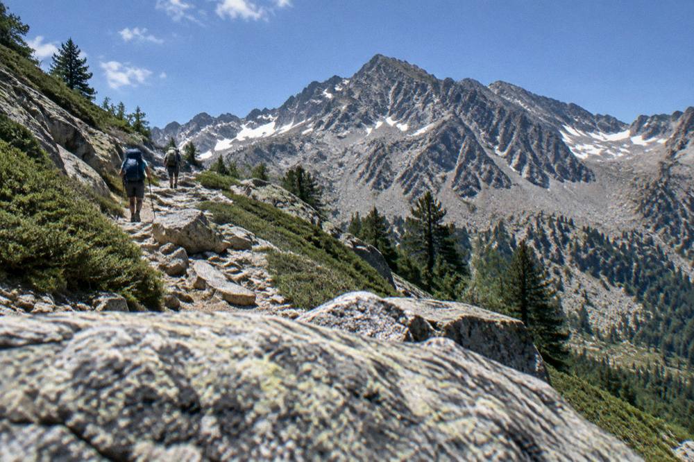 Hikers on a stony mountain path high above the forests of central Corsica