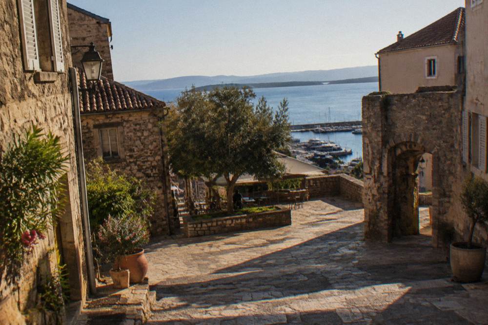 Stone houses and a small square in a Corsican seaside village in warm afternoon light