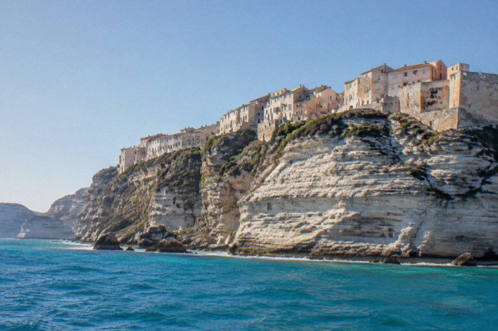Bonifacio's tall white cliffs rising above turquoise water seen from a boat