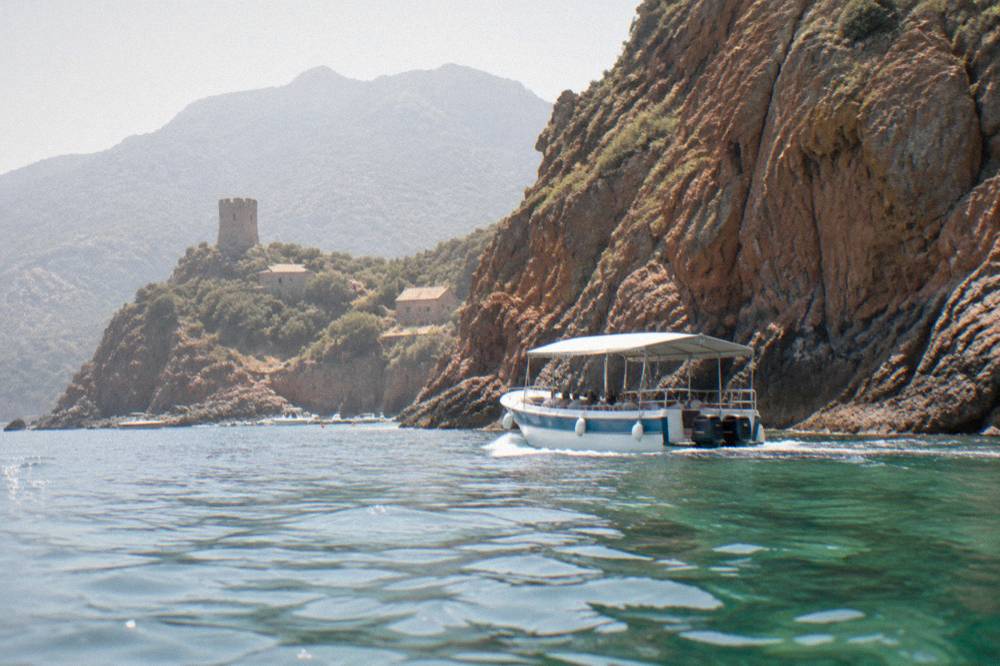A covered excursion boat cruising close to steep rock walls above the waterline