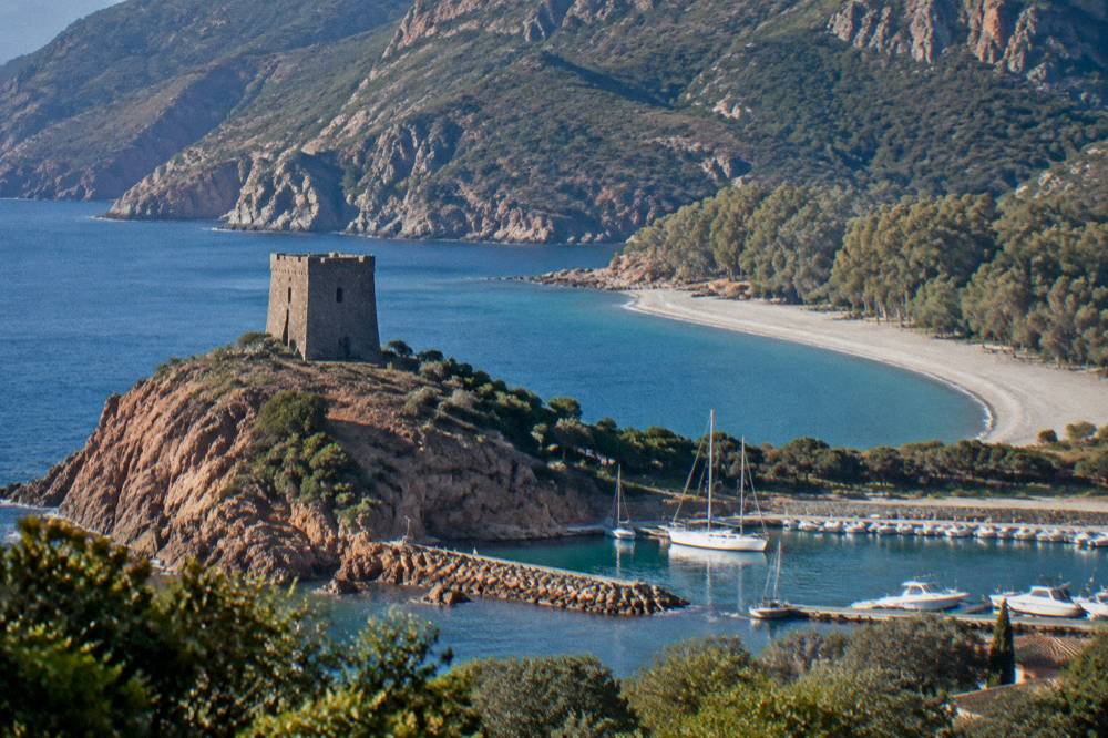 A stone watchtower on a headland above a curved sandy beach