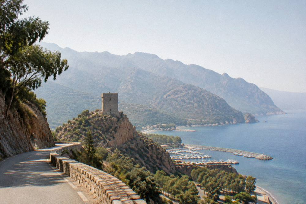 A narrow coastal road winding along a cliff above the sea