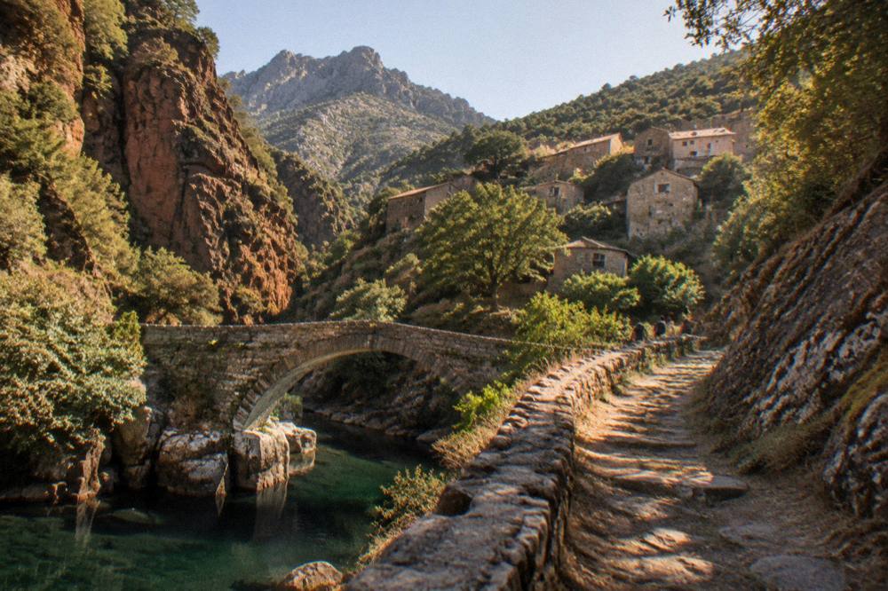 A stone village of small houses on a forested mountainside