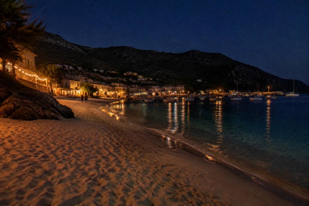 Harbour town waterfront with moored boats and low buildings beneath hills at dusk