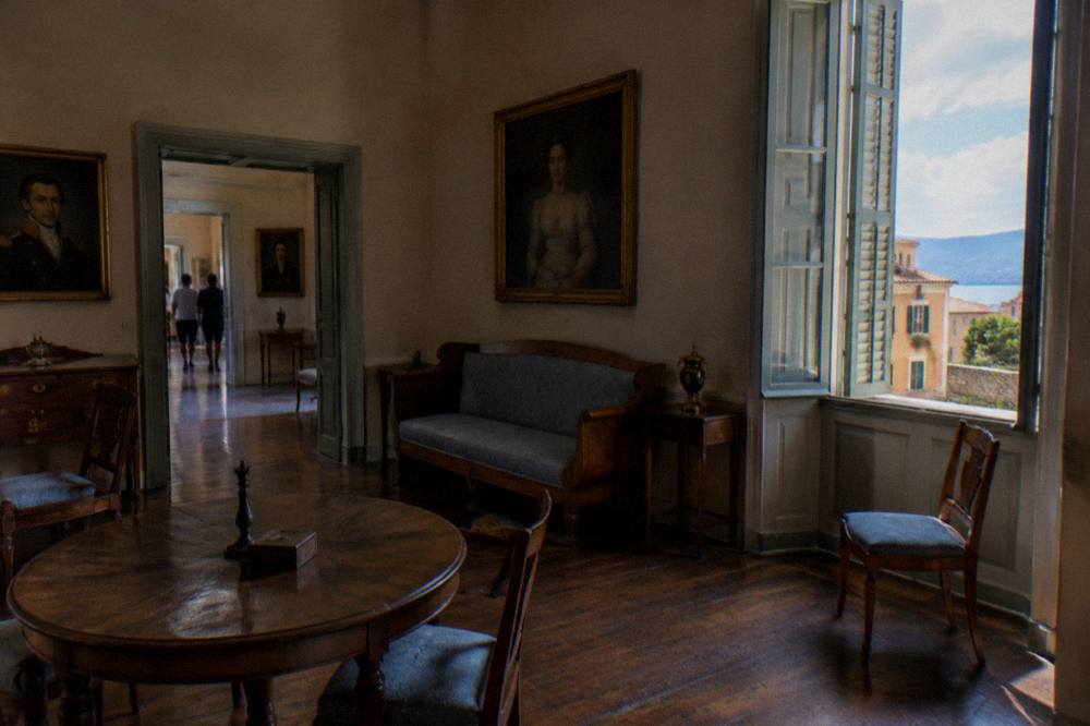 Interior of a historic townhouse room with period furniture and tall shuttered windows