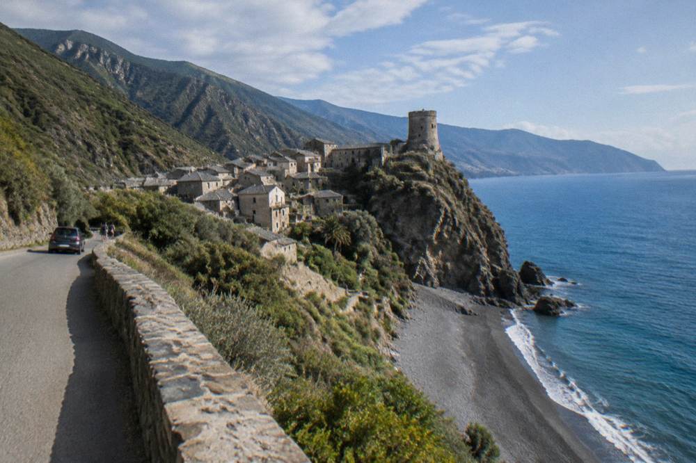 A coastal road winding along a hillside above blue Mediterranean water