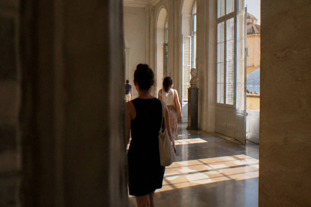 Visitors walking through a museum hall with tall windows