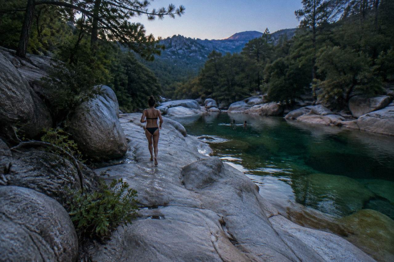 Clear green river pools between smooth granite rocks under pine trees