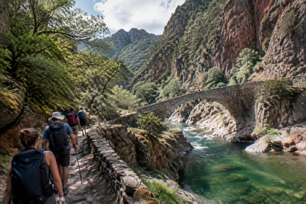 A guide leading a small group along a river canyon in Corsica