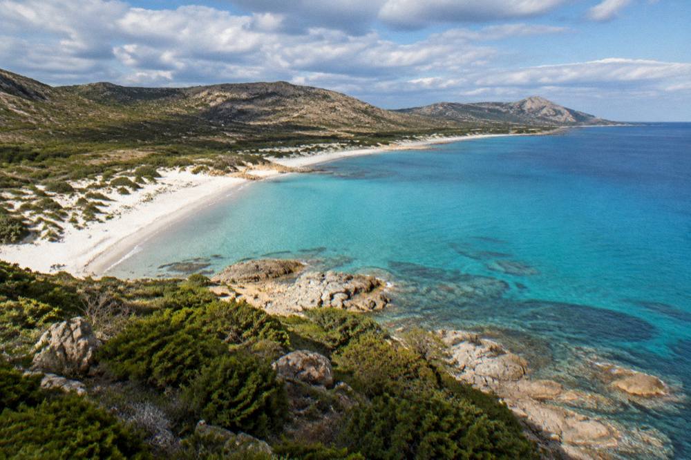 The southern Corsican coastline seen from above with sand, rocks and open sea reaching to the horizon
