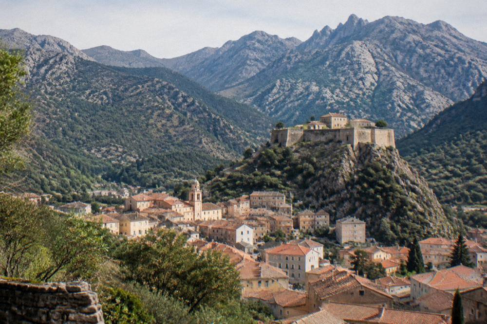 The town of Corte seen from a height, with red-roofed buildings below a citadel
