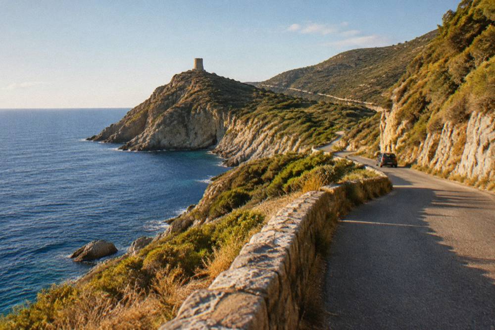 A winding coastal road above the sea in southern Corsica with scrub-covered hills