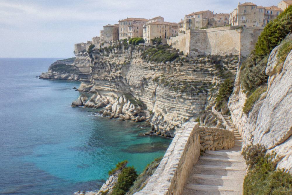A stone staircase carved into a white cliff above blue sea