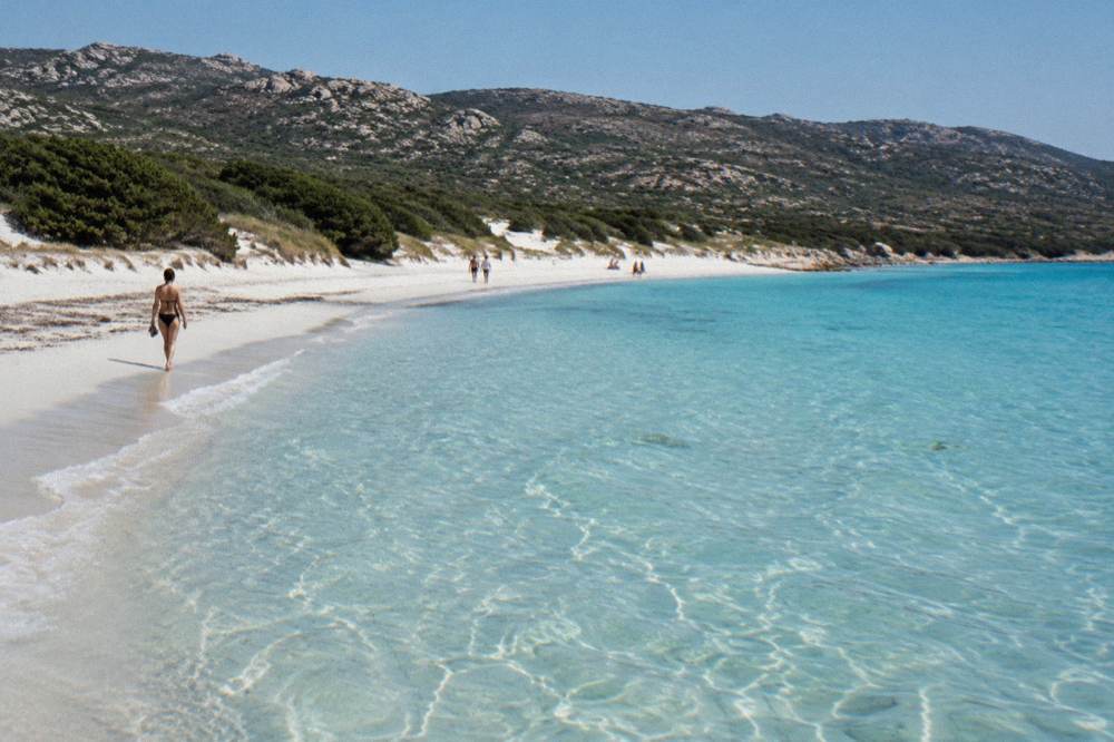 Clear shallow water over pale sand with gentle ripples reaching the shore