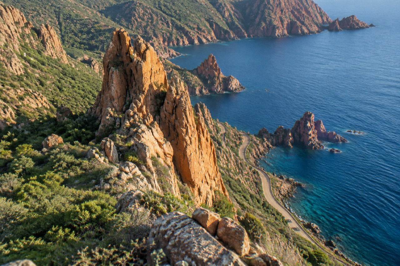 Red volcanic cliffs rising from clear water along the Corsican coastline