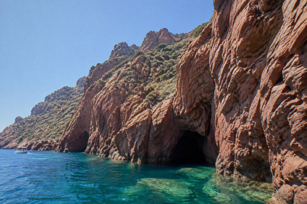 Clear turquoise water against red rock at the base of a sea cliff