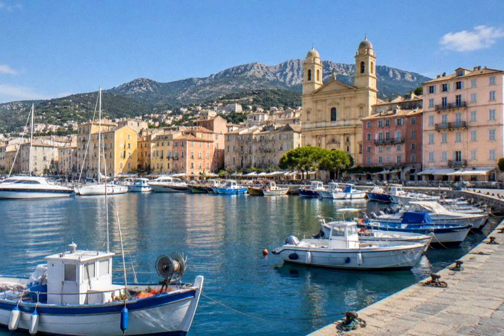 Fishing boats and tall ochre houses around a small harbour at golden hour