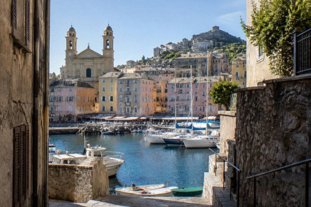 Narrow street of stone buildings climbing from the old harbour toward the citadel in Bastia