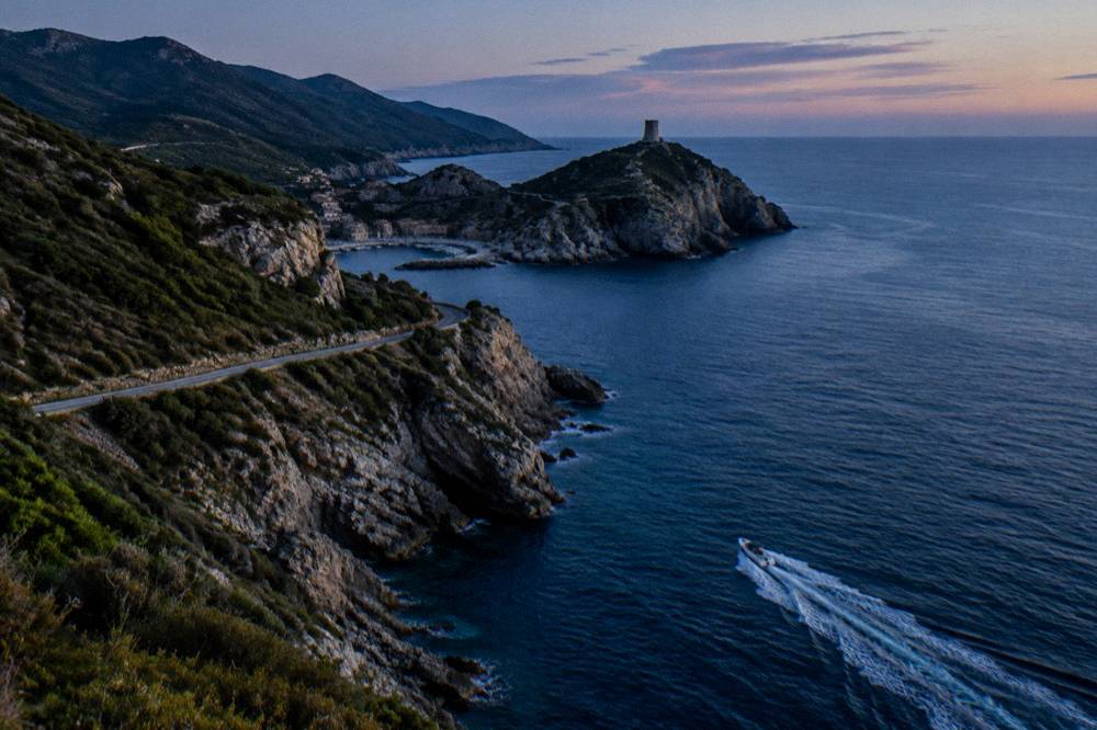 Boat at speed along the rocky coastline of Cap Corse north of Bastia, Corsica