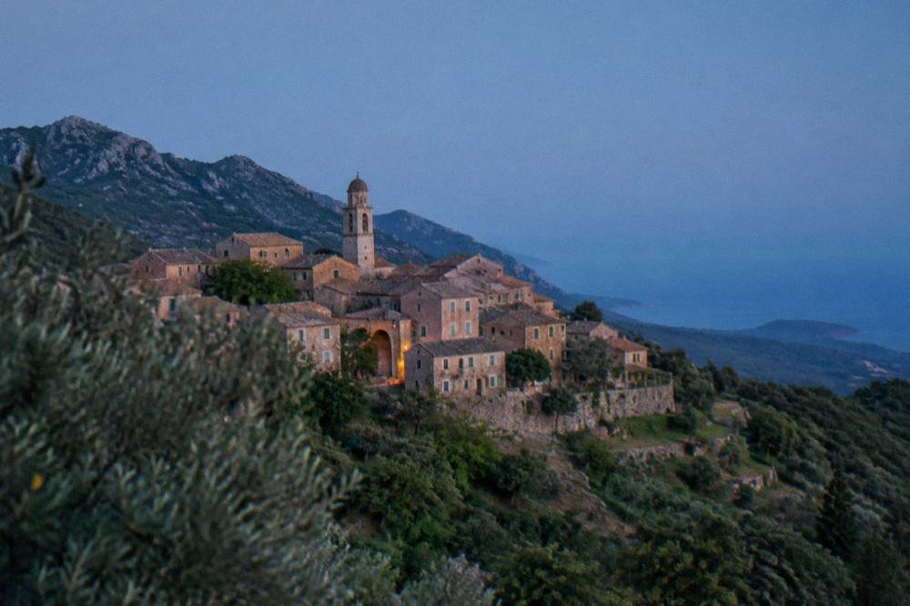 A stone hilltop village in the Balagne interior of Corsica under a clear sky