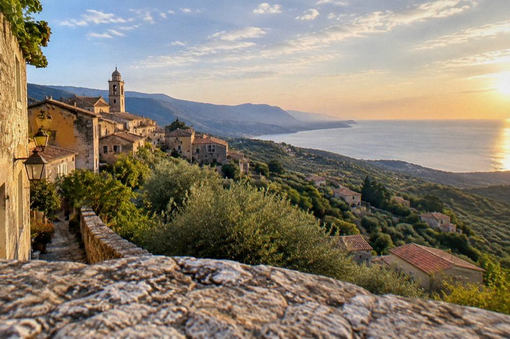 A panoramic view of the Balagne coastline of Corsica with hills and sea at golden hour